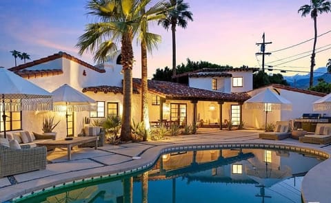 Lush palm-lined pool with chic loungers, umbrellas, and Spanish desert charm.