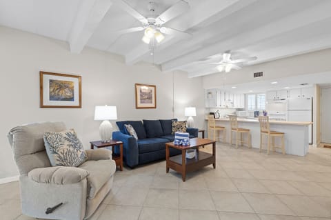Relax in this open beach-style living area with cozy seating and a spacious kitchen and bar. Perfect for unwinding after a sunny day by the shore.