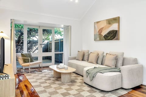 Step into the calming living area, where a TV, soft seating, warm lighting, and soothing artwork create a welcoming space to unwind.