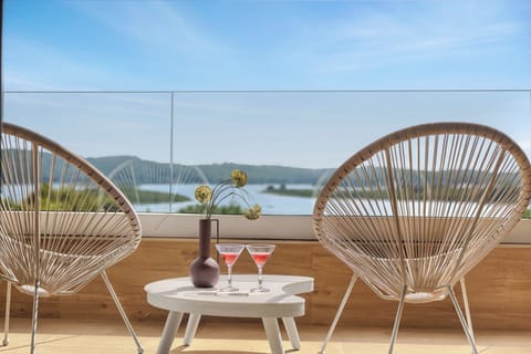 Balcony with sea view, lounge chairs, drinks table, and relaxing sunset vibe