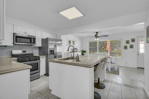 Bright kitchen and dining combo with island seating and backyard views — dinner and a show