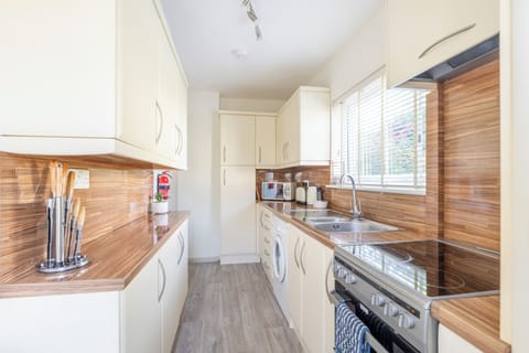 An image of the kitchen featuring an oven with stove top, sink, and a washer
