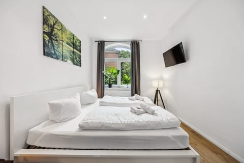 Ein helles, modern eingerichtetes Schlafzimmer mit gemütlichem Doppelbett, stilvollen Details und großem Fenster lädt zum Entspannen und Wohlfühlen ein.
