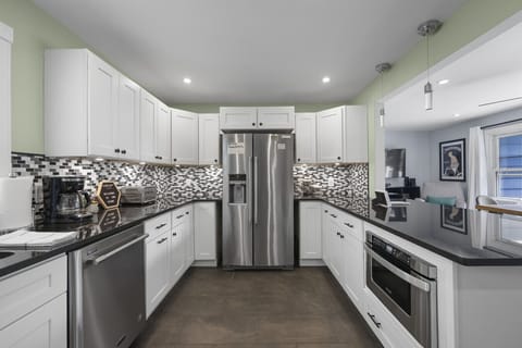 Spacious kitchen with stainless steel refrigerator, breakfast bar seating, and open layout.