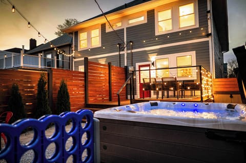 Relax in a serene backyard oasis with a bubbling hot tub, warm string lights, and cozy wood fencing. The glowing lights, rich wood, and cool blue tones create a peaceful, inviting atmosphere perfect for unwinding under the stars.