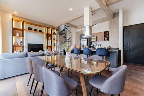 Open-concept living and dining area with a large table, unique chairs, and modern decor.