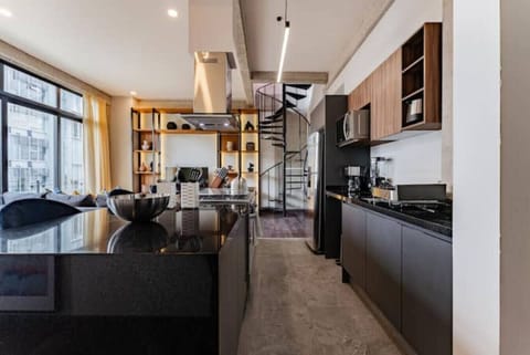 Modern kitchen with a black island, concrete floors, and industrial lighting.