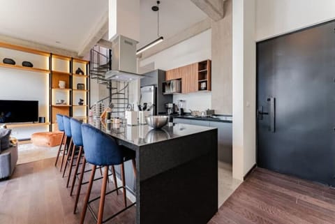 Contemporary kitchen with dark countertops, blue bar stools, and open shelving.