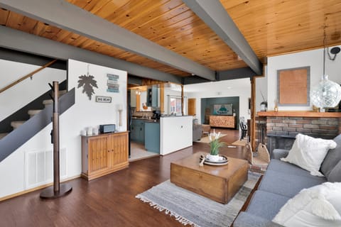 Cozy mountain living room with a stone fireplace, comfy seating, and smart TV—perfect for relaxing evenings, movie nights, and warm cabin vibes after outdoor adventures.