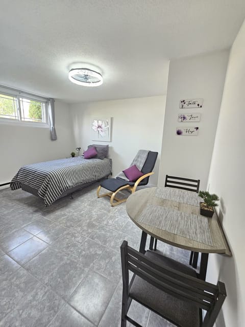 Cozy bachelor suite with XL twin sized bed, lounge chair, and dining nook