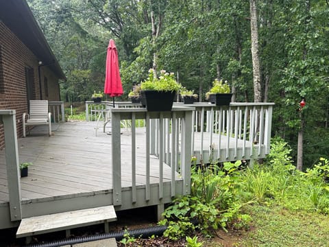 Rear deck that overlooks woods with dining table.
