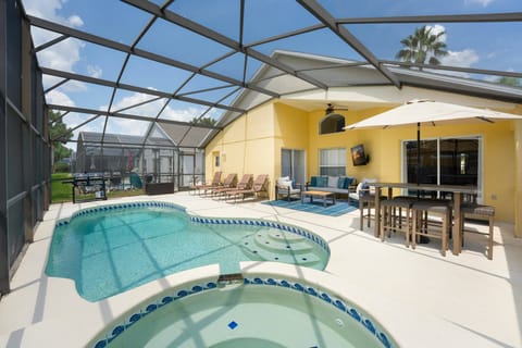 Discover a sunlit outdoor oasis with a sparkling pool and bubbling spa, surrounded by a sleek mesh canopy. The cheerful yellow walls and stylish seating invite you to relax and enjoy your day in this vibrant retreat.