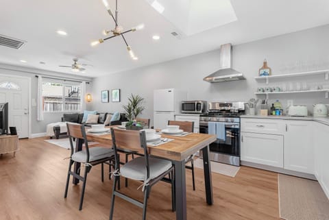 Modern dining area with wooden table and set for four, adjacent to a cozy living room.
