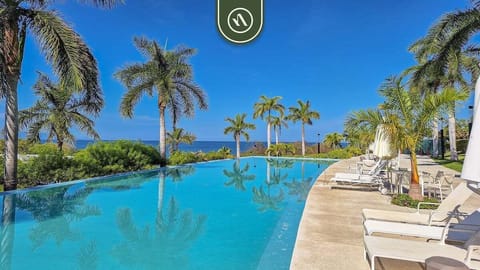 Stunning infinity-style pool surrounded by palm trees and ocean views. Lounge poolside in a peaceful tropical setting, ideal for sunbathing, swimming, and soaking in coastal tranquility.