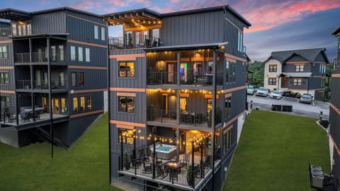 Modern multi-story building with spacious balconies and outdoor seating areas lit by string lights at dusk