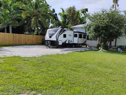 Gravel lot with foliage and privacy fence, included electricity and water.