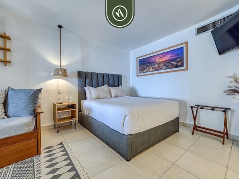 Simple, bright bedroom layout featuring a double bed and a patterned floor rug.