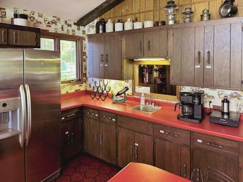 View of the wet bar within the full kitchen space with a serving window to the main entrance hallway & additional wine & beverage refrigerator