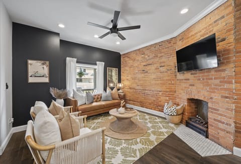 Relax in the cozy living room with exposed brick walls and stylish decor - Comfortable seating and smart TV create the perfect gathering spot - Natural light fills this inviting modern space