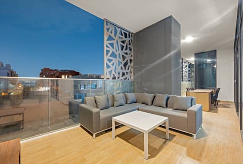 Balcony Retreat: Unwind on a stylish couch with stunning city views under the evening sky!