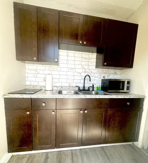 Kitchen equipped with two burners, blender, toaster, microwave and utensils.
