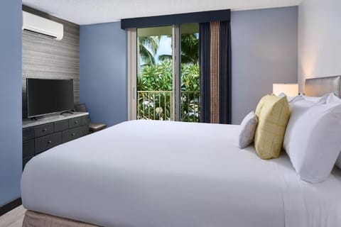 Lounge in bed with tropical views and cool AC comfort.