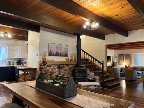 Modern rustic cabin interior with wood beams, stove, and cozy open-concept seating area.