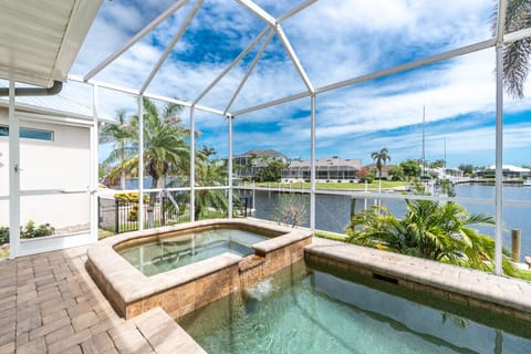 Screened spa and pool with palm-lined views.