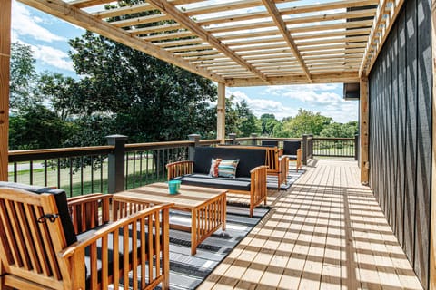 Spacious deck with wooden seating and pergola.