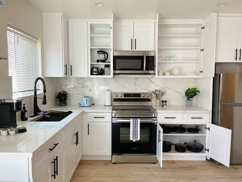 Full kitchen stocked with electric kettle, blender, pots/pans, and dishware.