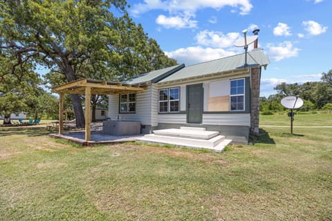 Charming cabin with a green metal roof, shaded patio, and peaceful country views.