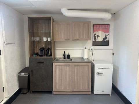 Entry room bar sink, Nespresso, mini-fridge, plates, cups, cutlery.