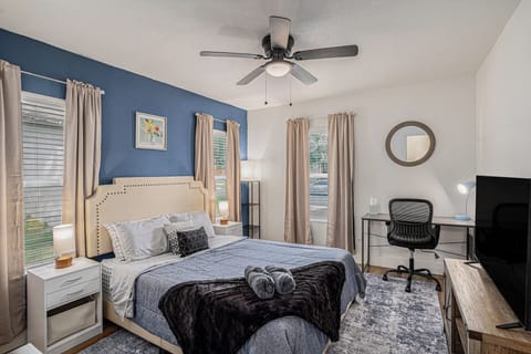 Cozy bedroom with desk, TV, plush bedding, and built-in charging ports.