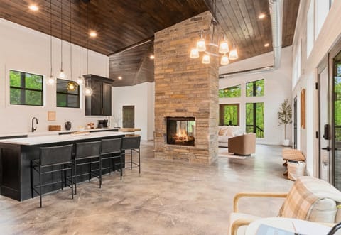 This stunning kitchen and living area is the heart of the home, boasting high ceilings, a statement stone fireplace, and a seamless flow to outdoor spaces.