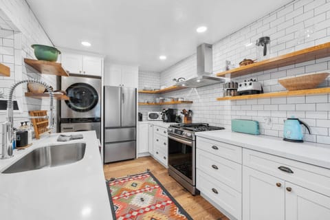 Fully stocked kitchen with gas range, fridge, and open shelving.