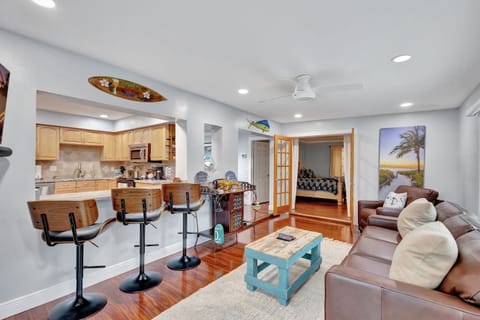 Bright Florida sunroom with bar seating, flowing gracefully toward the primary bedroom’s French doors.