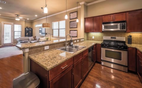 View of kitchen sink, dishwasher, oven, microwave