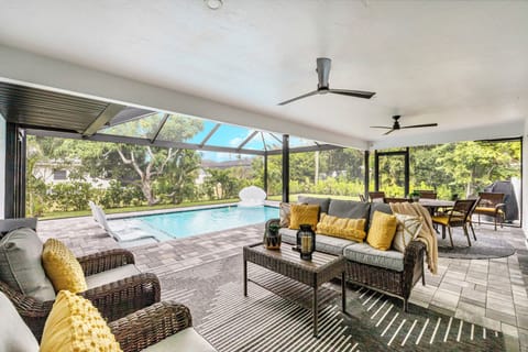 Unwind in the shaded lanai with cozy seating, ceiling fans, and serene pool view