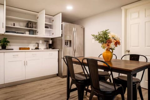 Fully equipped kitchen with stainless steel appliances, open shelving, and a cozy dining area accented by fresh flowers 🌿🍴✨