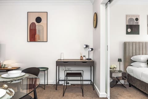 Step into this apartment with a comfortable bedroom (featuring "Bauhaus" art), a chic dining/living area, and a convenient dedicated workspace.