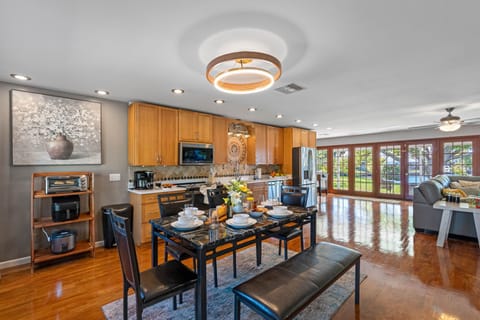 With a sleek black dining table, modern lighting, and a fresh floral centerpiece, the space balances elegance with casual charm.