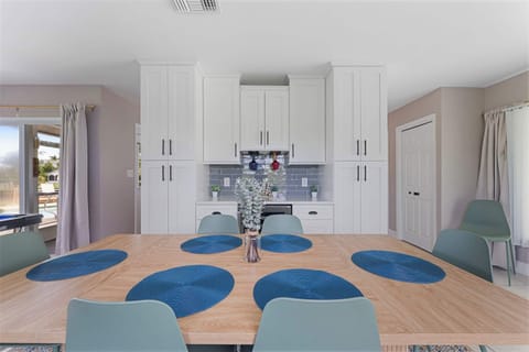 Spacious dining area with seating for six, bright natural light, and a stylish coastal vibe.