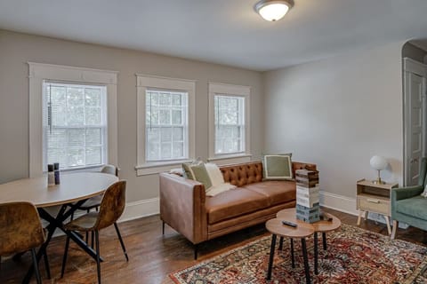 Cozy living area with a brown leather couch, wooden table, and patterned rug.