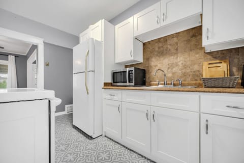 Fully stocked kitchen with crisp white cabinetry, microwave & full-size fridge