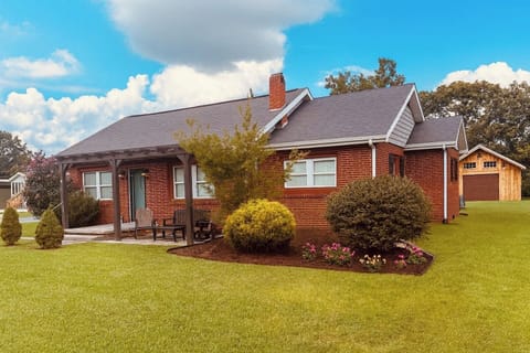 This inviting brick cottage features a cozy front porch with rocker and bench seating, perfect for morning coffee or evening relaxation. Surrounded by a spacious yard, as well as large back patio, it offers the perfect blend of comfort and charm. 