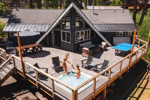 Multi-level deck with hot tub, lounge seating, and cabin views.
