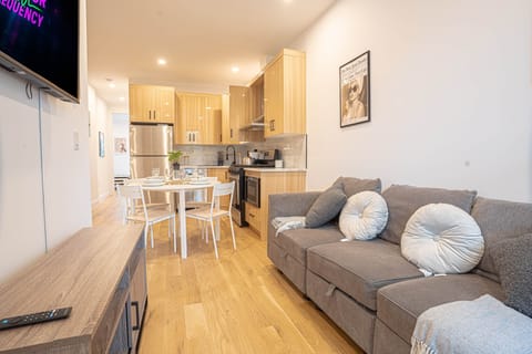 Cozy living area with modern kitchen, dining for four, plush sofa and warm wooden flooring.