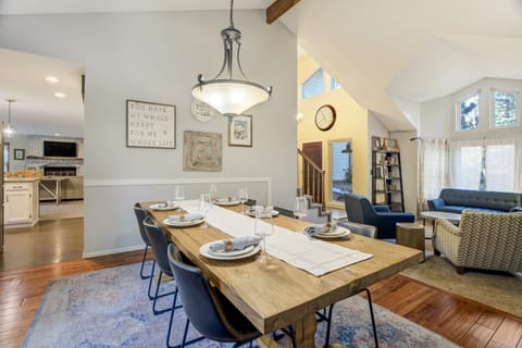 Beautiful dining area for six in an open-concept layout, with sightlines into the front sitting room, kitchen, and main living room with TV.