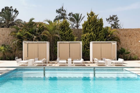 Lounge lazily poolside in shaded cabanas beside sparkling water.
