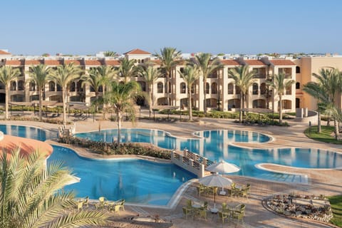 Lounge poolside while elegant resort buildings frame the view.